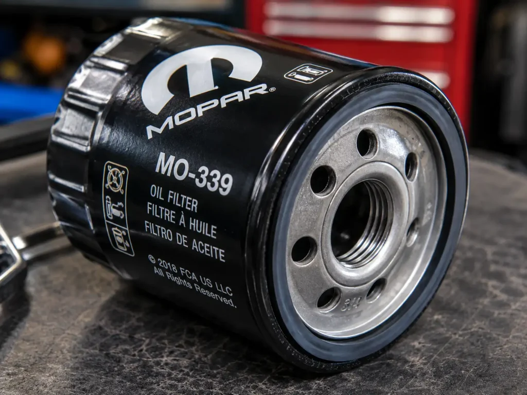 Macro close-up of a Mopar MO-339 oil filter showing printed label, rubber gasket, and threaded center opening in a workshop setting.