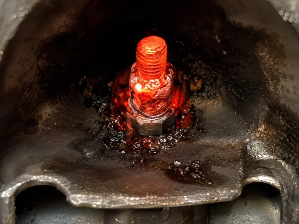 Glowing red-hot electrical stud and nut inside a diesel intake manifold showing heat and arcing damage