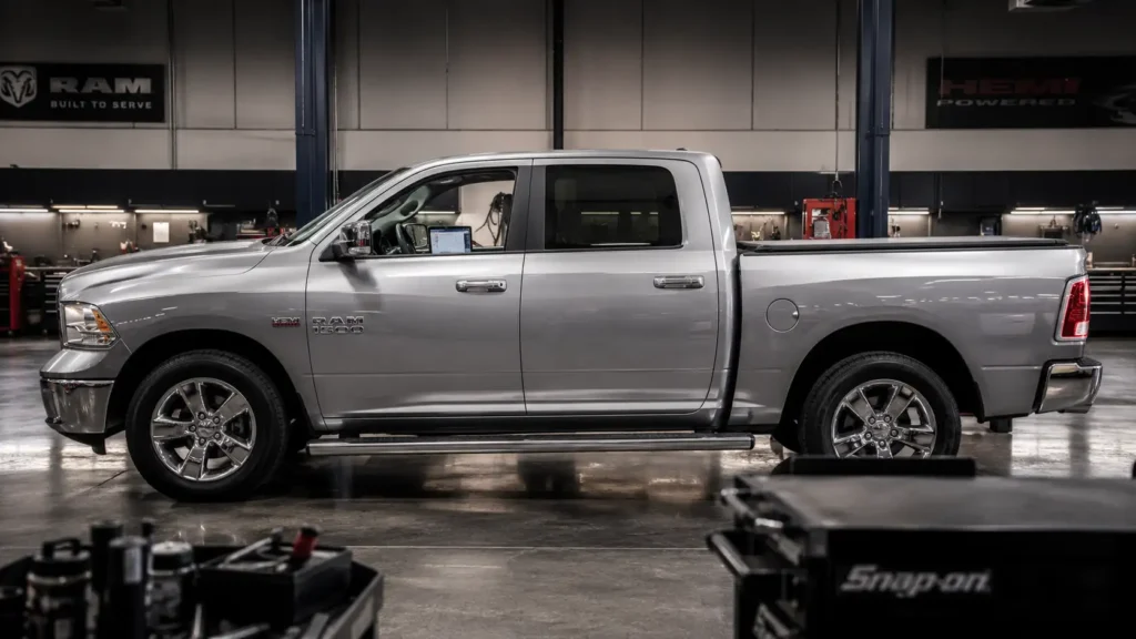 Silver Ram 1500 parked side-on inside a professional garage, with a diagnostic tablet visible through the driver-side window.