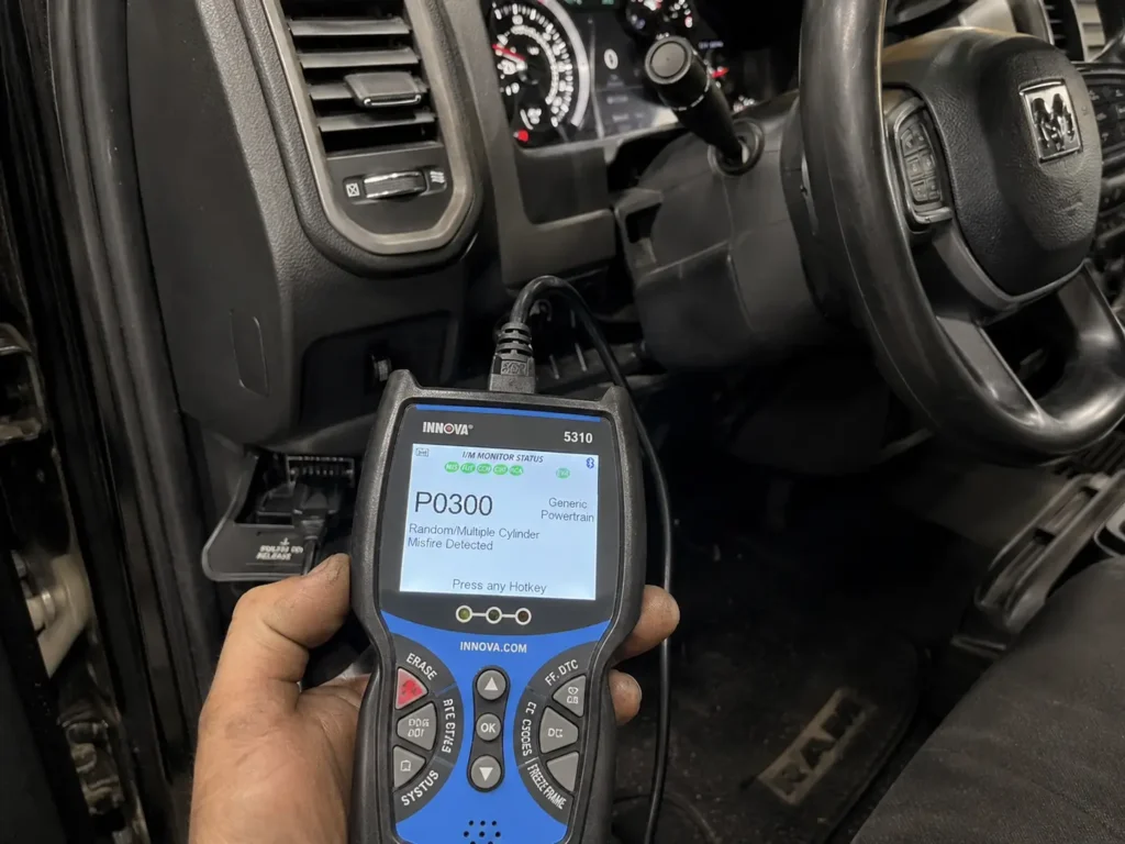 OBD-II scanner showing P0300 code plugged into Dodge Ram diagnostic port under dashboard